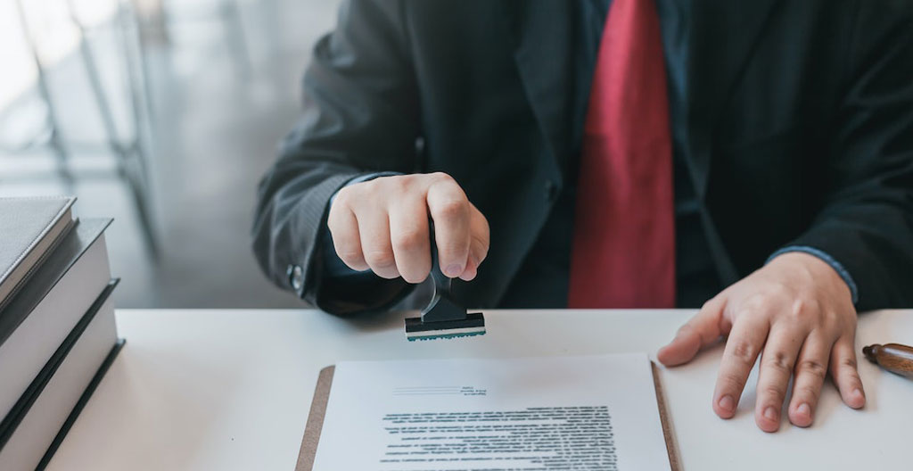 Technicien automobile certifié McLaren examinant attentivement un carnet d'entretien avec une loupe de précision, dans un atelier de centre agréé avec équipements de diagnostic en arrière-plan