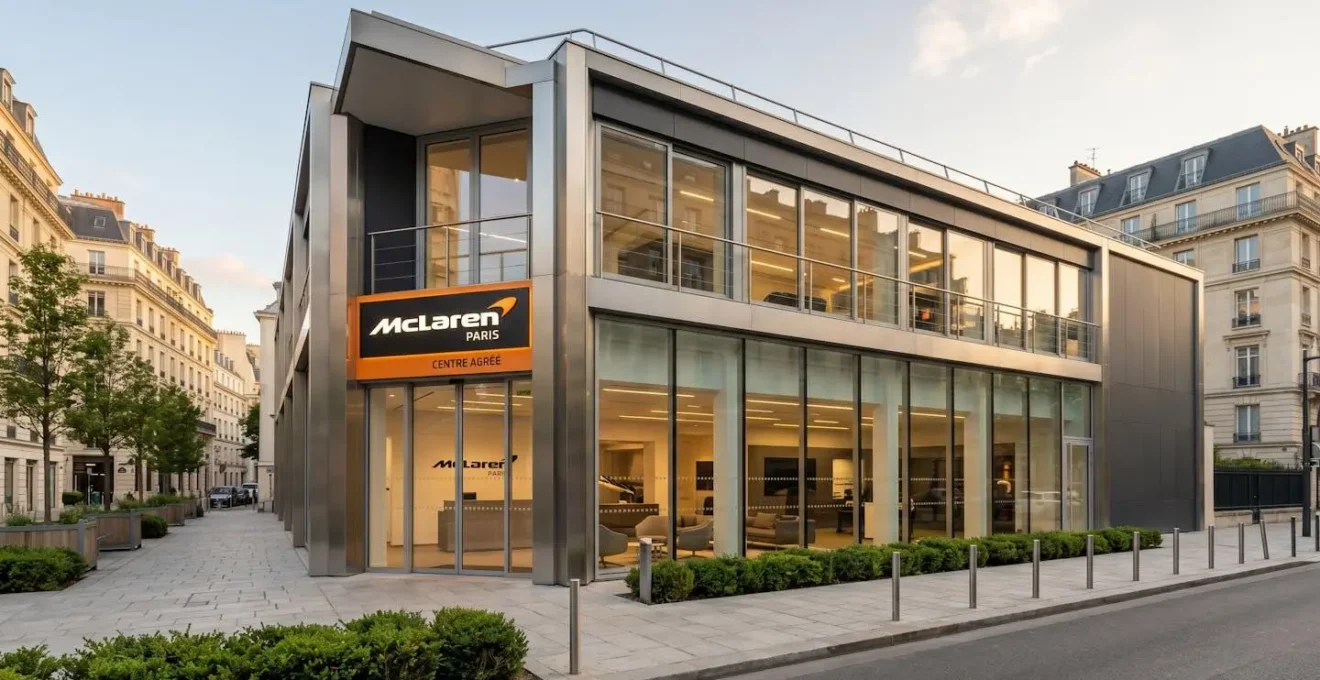 Façade contemporaine d'un centre McLaren agréé officiel en France, avec enseigne orange et noire visible, architecture haut de gamme en verre et acier, dans un contexte urbain premium