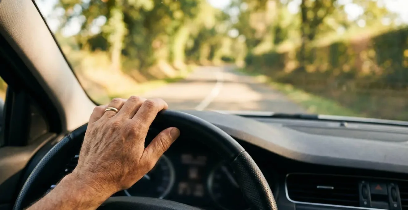 Conducteur français gardant les mains détendues sur le volant lors d'un trajet économe en carburant sur une route de campagne